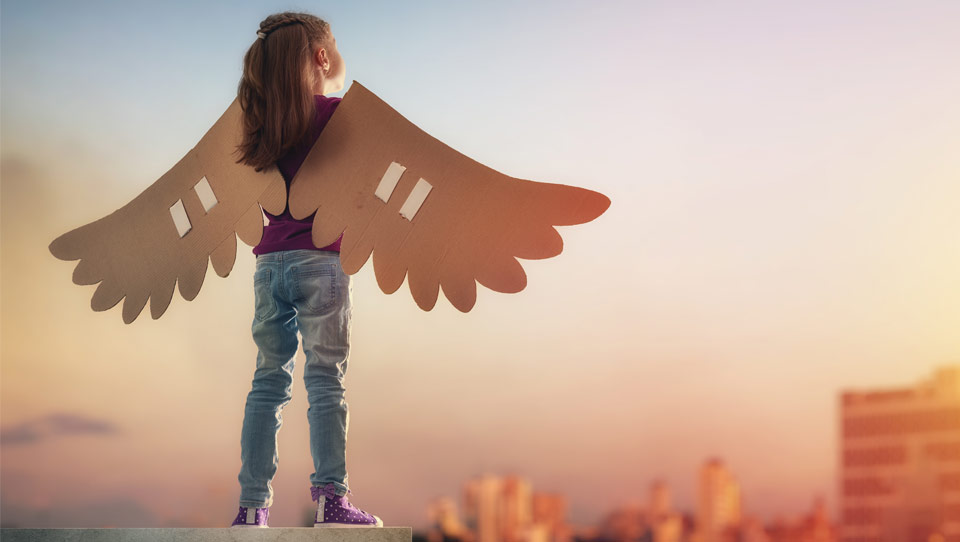 Petite fille de dos, portant des ailes en carton